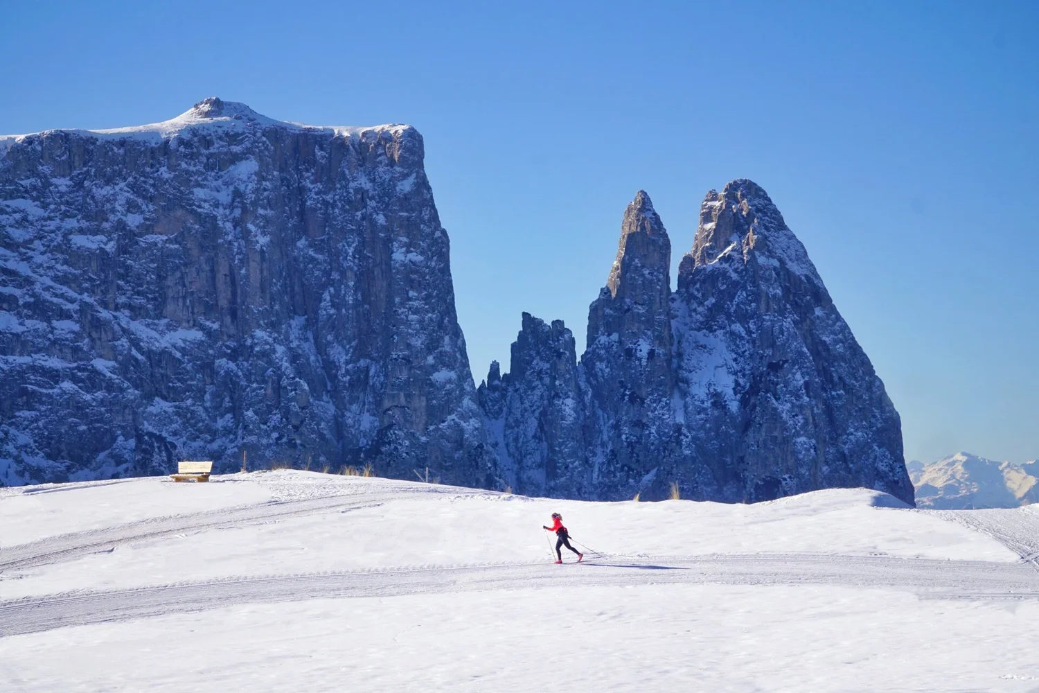 A skier on a groomed trail beneath the Dolomite peaks on a Lumi Experiences trip