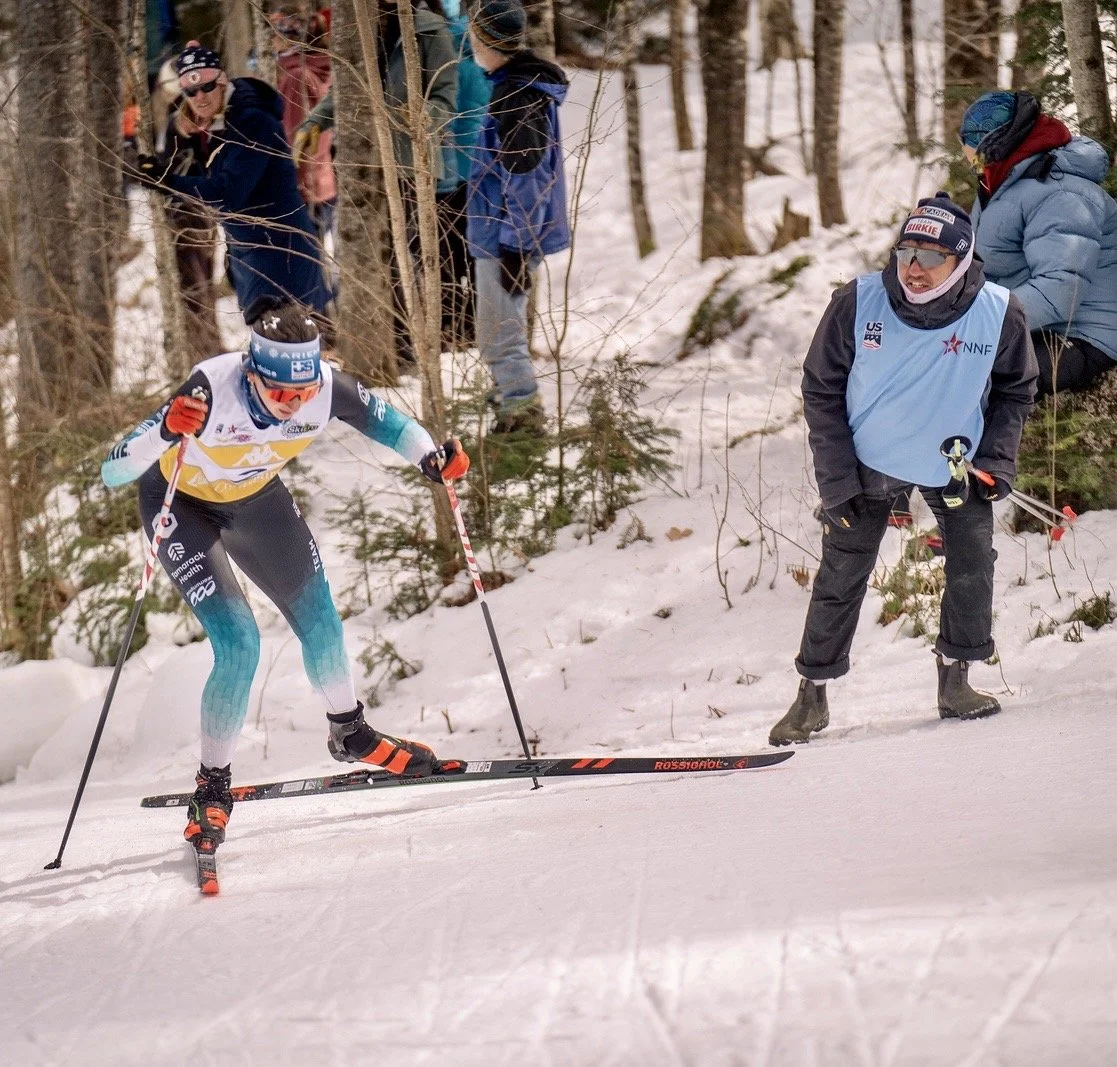Cross-country skier racing on snow with supporters alongside the course